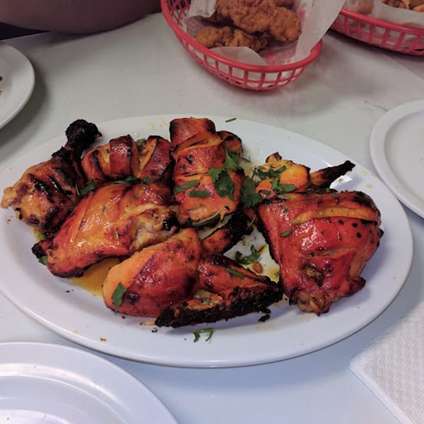 A white plate filled with grilled Pakistani chicken pieces, garnished with fresh cilantro.